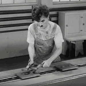 An animated Gif loop of Charlie Chaplin turning wrenches repeatedly to pointlessly adjust metal items moving down a conveyor belt