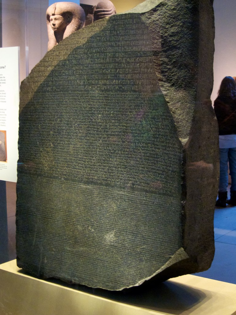 A photograph of a large stone slab in a glass case on display at the British Museum